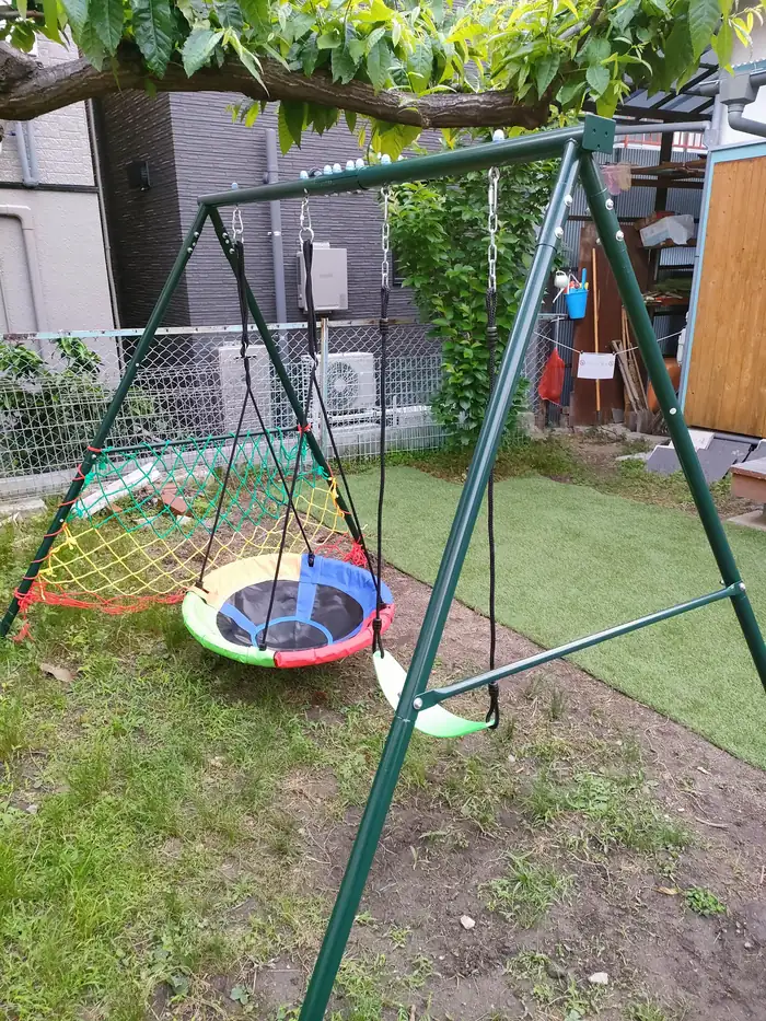 庭に設置されたブランコ。芝生と木々に囲まれている